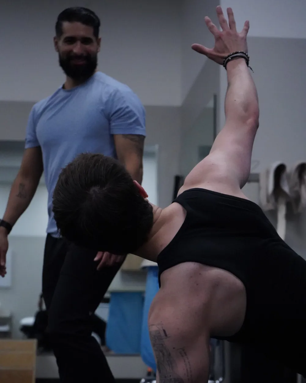 Dr. Rodriguez watching and smiling as a client reaches overhead in a windmill movement