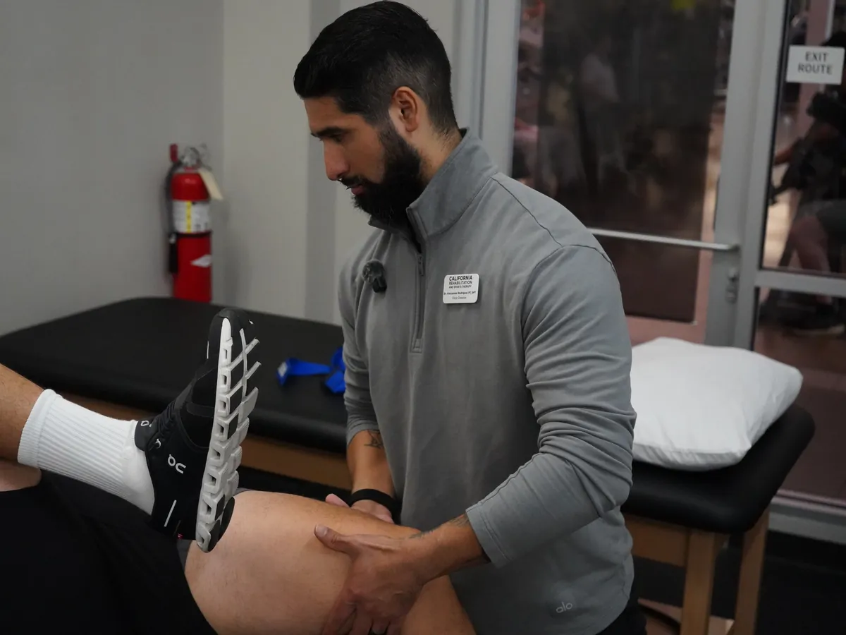 Dr. Rodriguez performing hands-on physical therapy treatment on a patient's thigh
