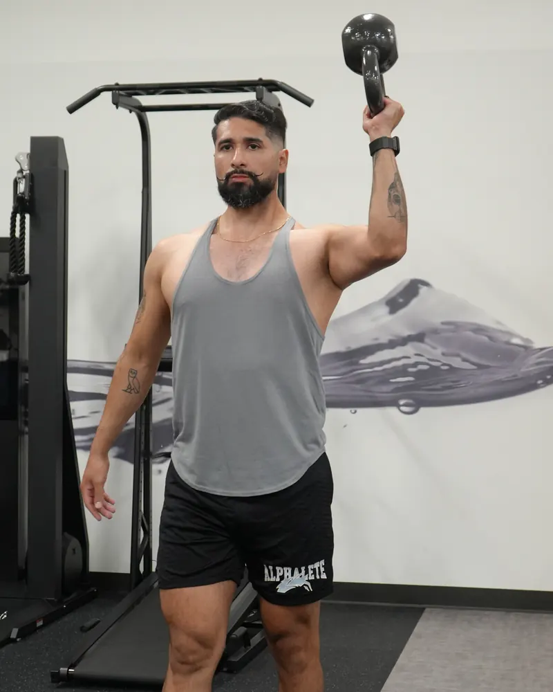Dr. Rodriguez holding a kettlebell overhead for a single-arm carry