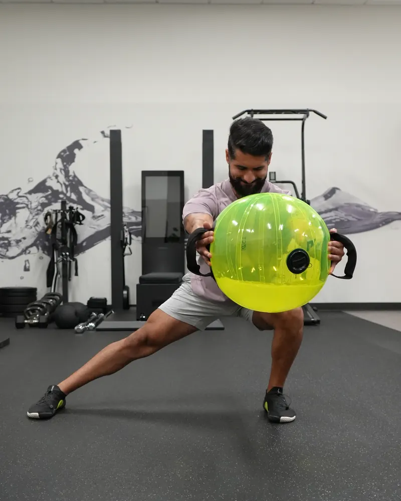 Dr. Rodriguez performing a lateral lunge while holding a water-filled training ball